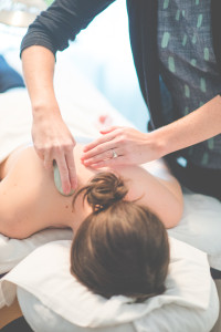 Close up of Allie Machen performing Gua sha on the back of a female patient.